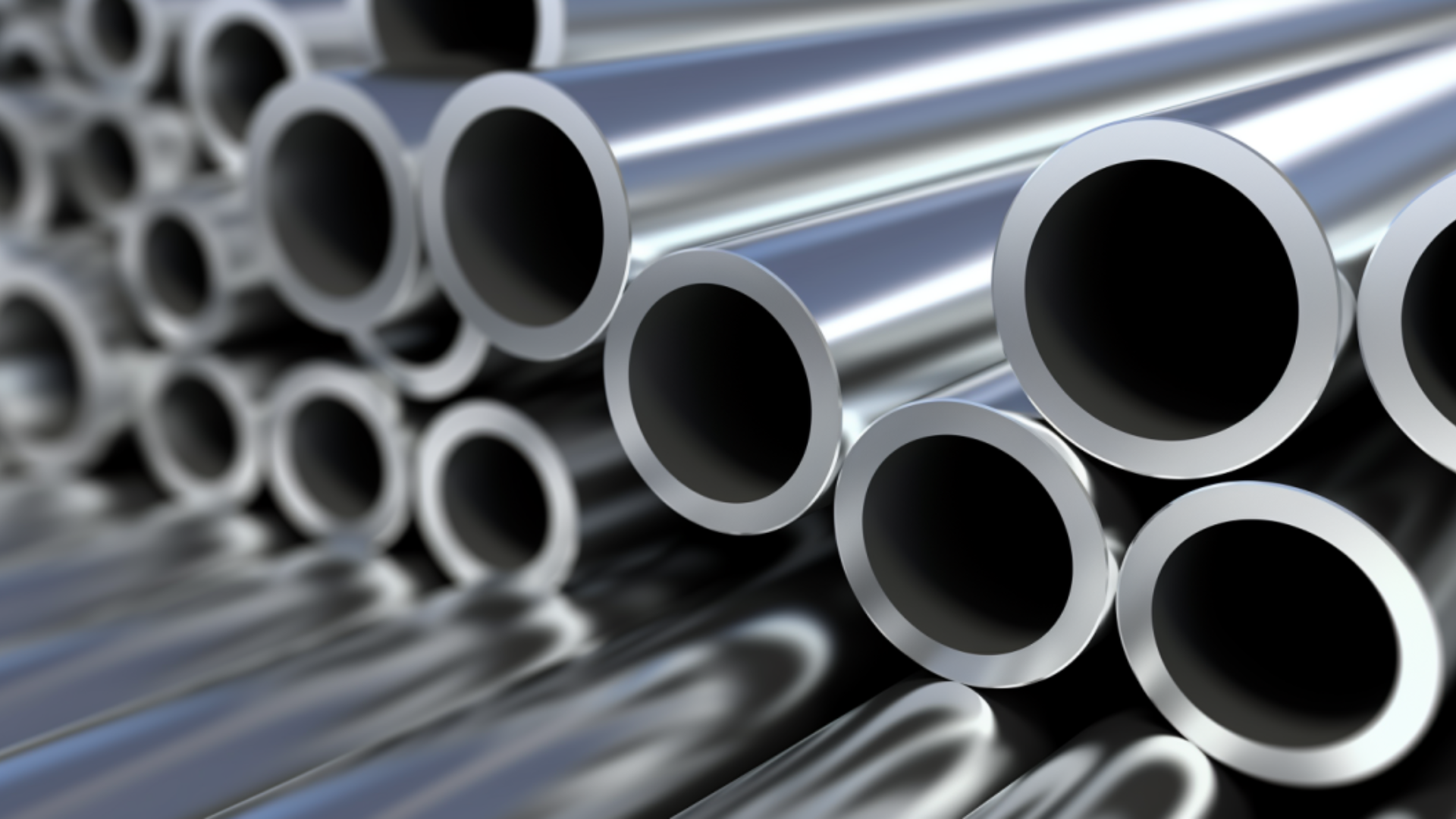 Silver metal tubes, stacked in close-up, reflecting light.